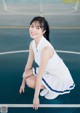 A woman in a white dress crouching on a basketball court.