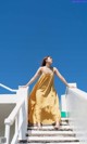 A woman in a yellow dress is walking up some stairs.